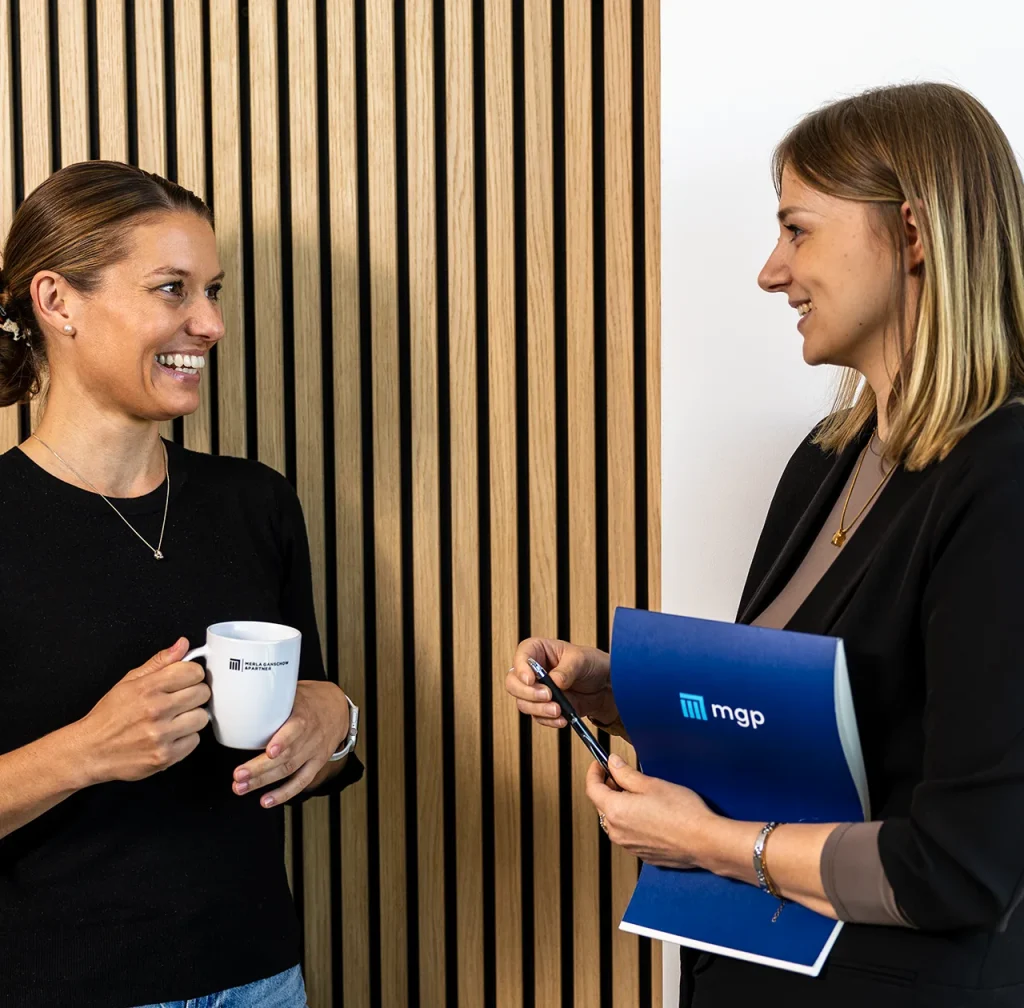 Die HR Mitarbeiterinnen Jenny & Katharina unterhalten sie freundlich miteinander.